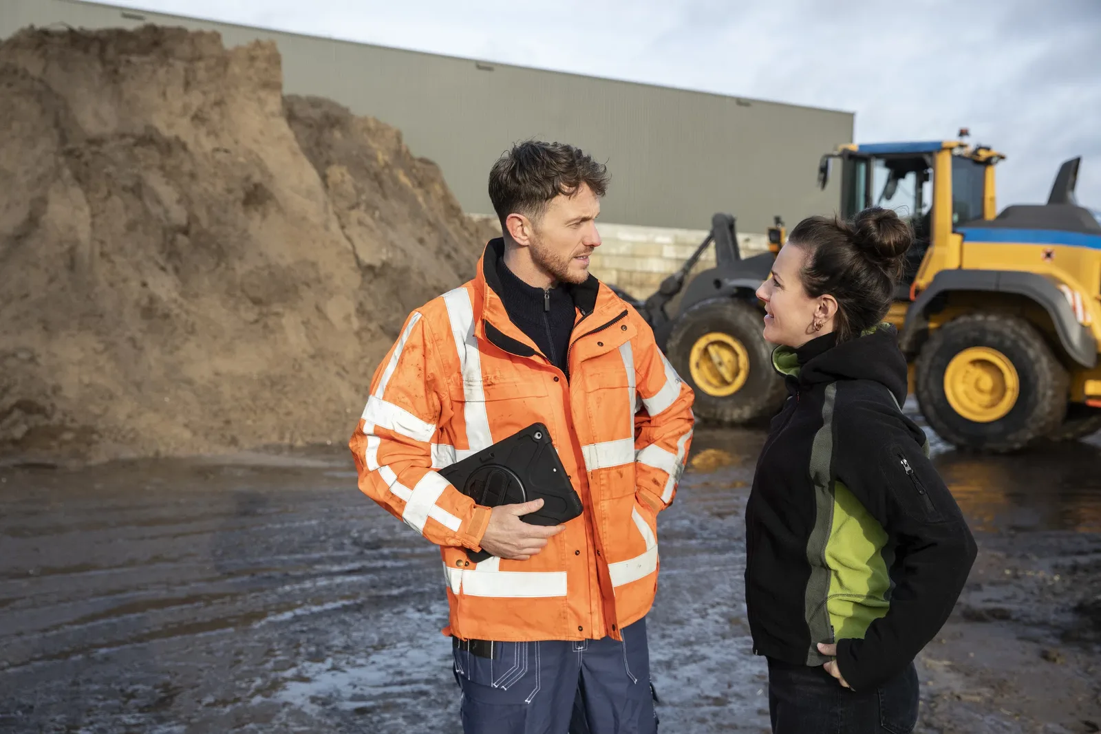 Twee bouwvakkers bekijken samen een tablet op de bouwplaats